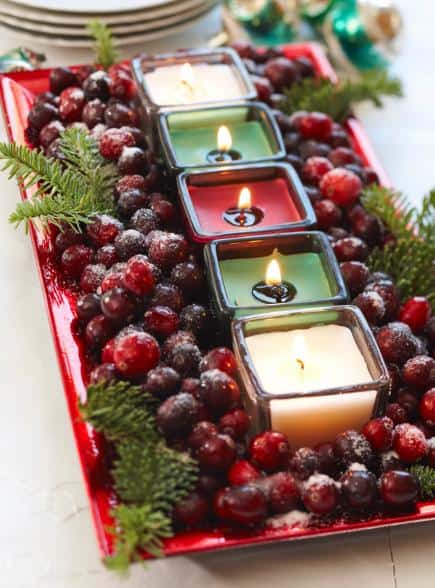 cranberries and pine sprigs surround votive candles