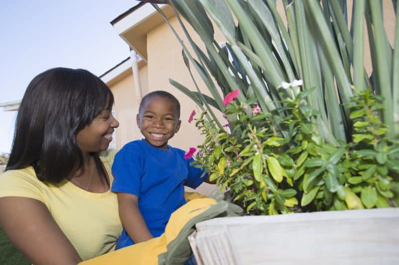 Preschooler garden activity - boy playing in garden with mom.