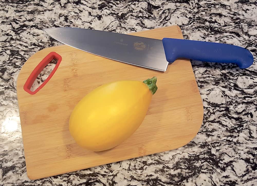 golden egg squash on cutting board with knife