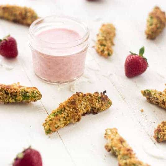 Granola coated avocado fries on white background with strawberries and pink dipping sauce.