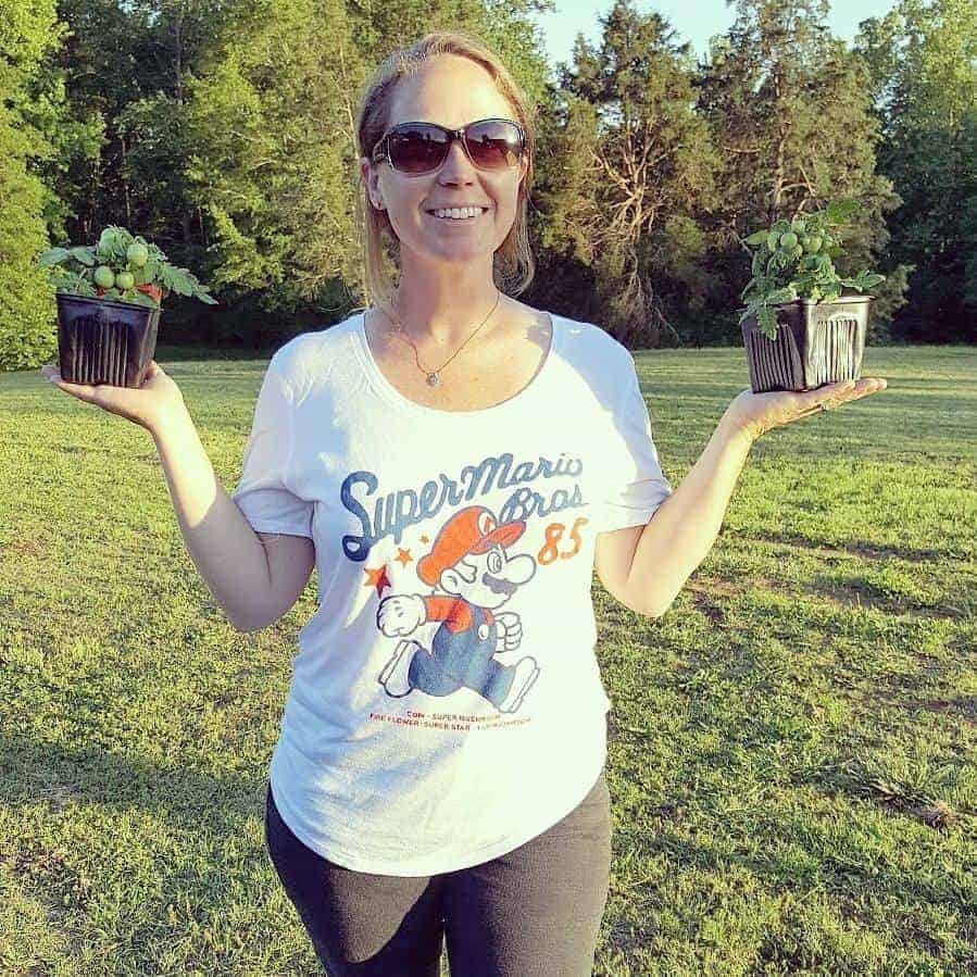 Laura, author at Youshouldgrow.com, holding two miniature tomato plants.