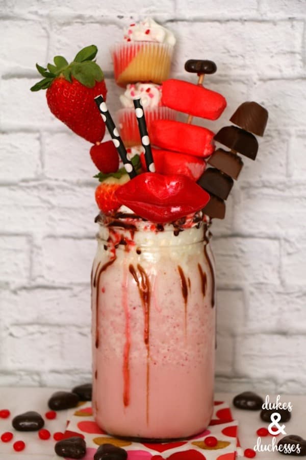 strawberry extreme milkshake topped with cupcakes, strawberries, candy, and wax lips