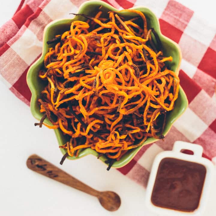 Spiralized sweet potato fries in bowl with sauce