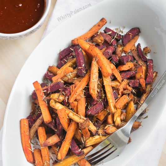 Colorful fries from carrots and beets on a white plate with bbq dipping sauce.